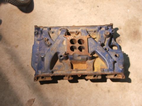 1965 Ford Mustang - A blue engine intake manifold sits on a concrete floor, showing signs of rust and wear.