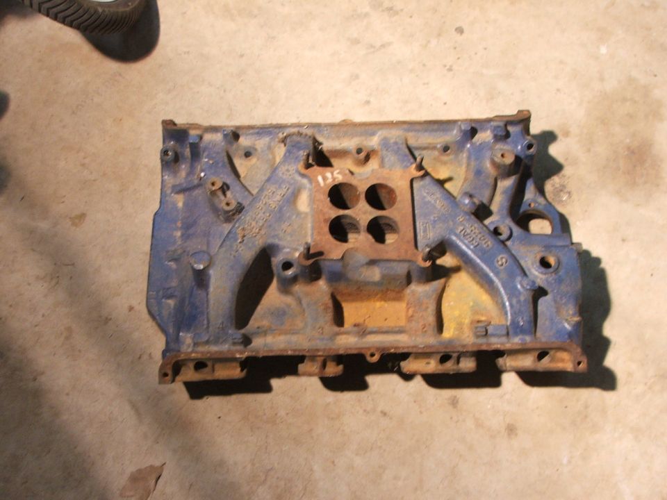 Blue painted engine intake manifold with rust and four circular openings