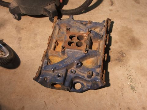 1965 Ford Mustang - This blue engine intake manifold features four bolt holes for carburetor mounting and visible casting numbers.
