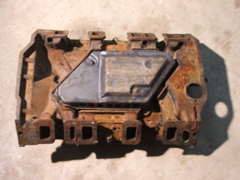 1965 Ford Mustang - This heavily rusted engine part features a gray cover plate and square ports, suggesting it's a component from an older vehicle.
