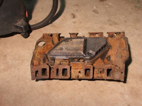 1965 Ford Mustang - This heavily rusted intake manifold is a part that may be from a 1965 Ford Mustang, but it is not definitively identifiable.