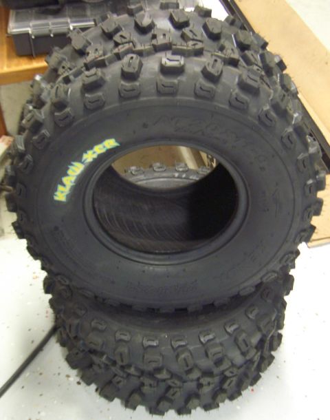 1974 Ford Bronco - Two knobby ATV tires are stacked, with a third tire visible above them. Yellow lettering on the top tire reads 'KLAW'.