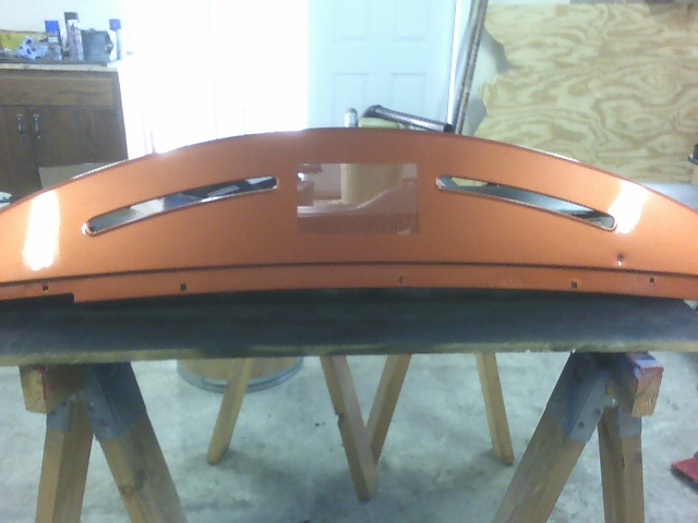 Orange dashboard section with two horizontal slots and a central rectangular cutout, resting on sawhorses