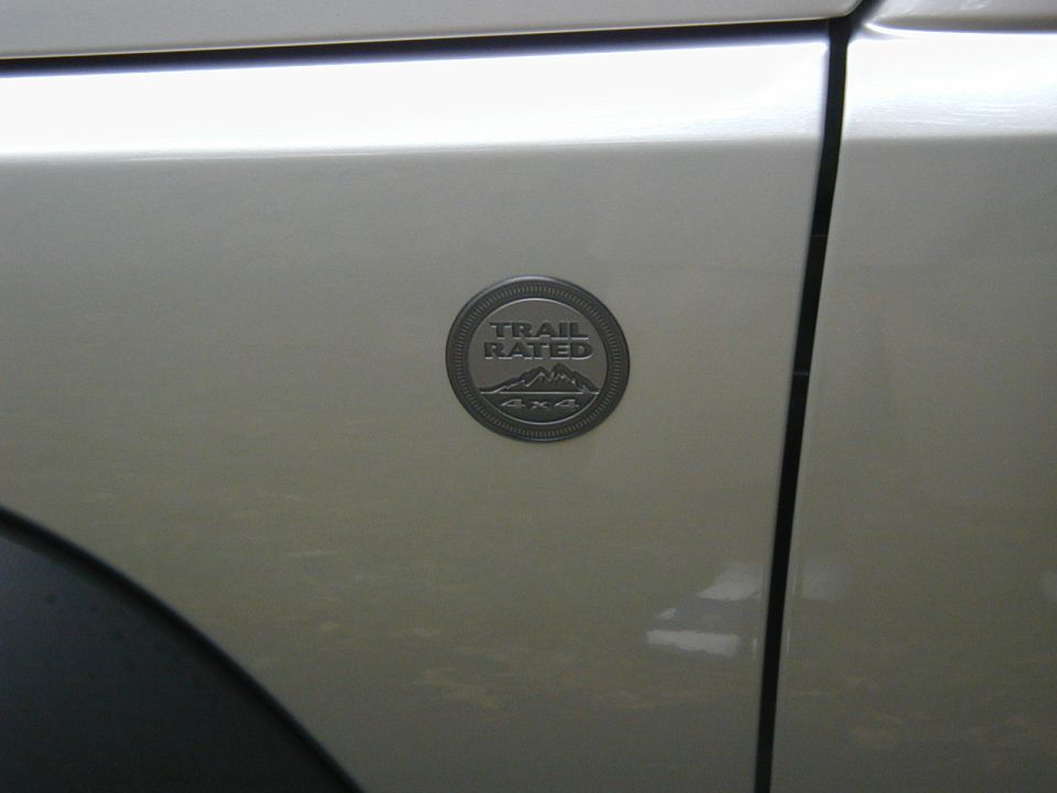 Close-up of a silver Jeep's fender showing the 'Trail Rated 4x4' badge