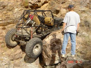 1994 Ford Bronco - A custom-built off-road buggy navigates a rocky incline, with a person observing nearby.