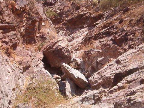 1994 Ford Bronco - A rocky hillside with sparse vegetation and large boulders is shown.
