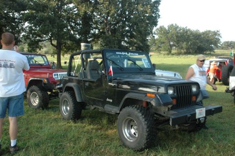 2001 Jeep Wrangler - A black Jeep Wrangler is parked in a grassy field with other vehicles and people.