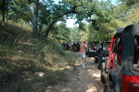 2001 Jeep Wrangler - A group of off-road vehicles are parked on a dirt trail surrounded by trees.