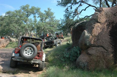 2001 Jeep Wrangler - Multiple Jeep Wranglers navigate a rocky, off-road trail under a clear blue sky.