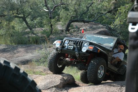 2001 Jeep Wrangler - A black Jeep Wrangler navigates a rocky trail with a driver inside.