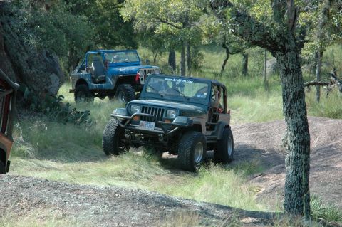 2001 Jeep Wrangler - Two Jeep Wranglers navigate a , off-road trail surrounded by trees and large rocks.