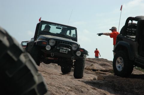 2001 Jeep Wrangler - Two Jeeps navigate a rocky terrain under a clear sky, with a person directing.