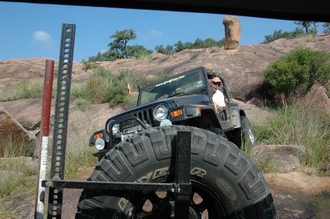 2001 Jeep Wrangler - Jeep Wrangler tackling a rocky trail, driver visible behind the wheel.