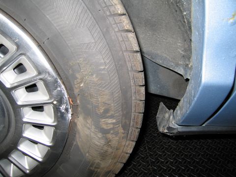 1991 Ford LTD Crown Victoria - Detail shot of a tire and wheel well, showing wear and tear on the body panel.