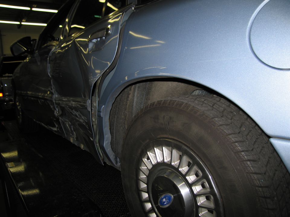 Blue 1991 Ford Crown Victoria LTD with dented rear passenger door and quarter panel, viewed from the side