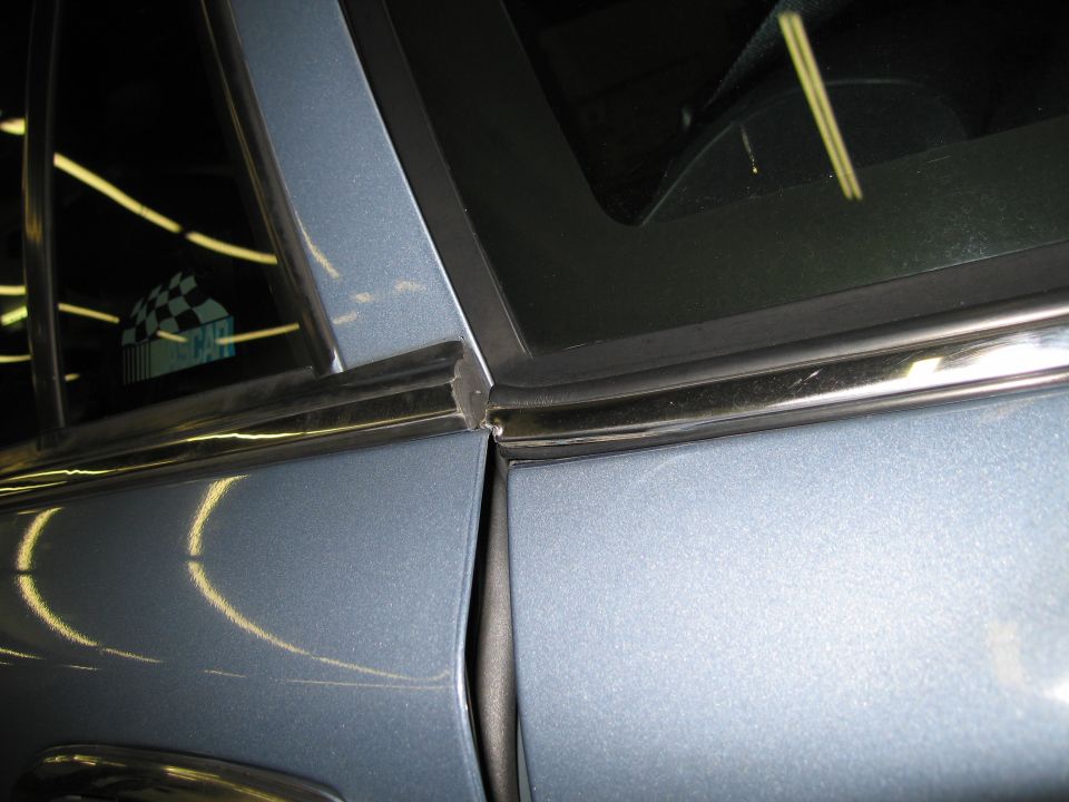 Blue car door seam with chrome trim and a checkered sticker on the window