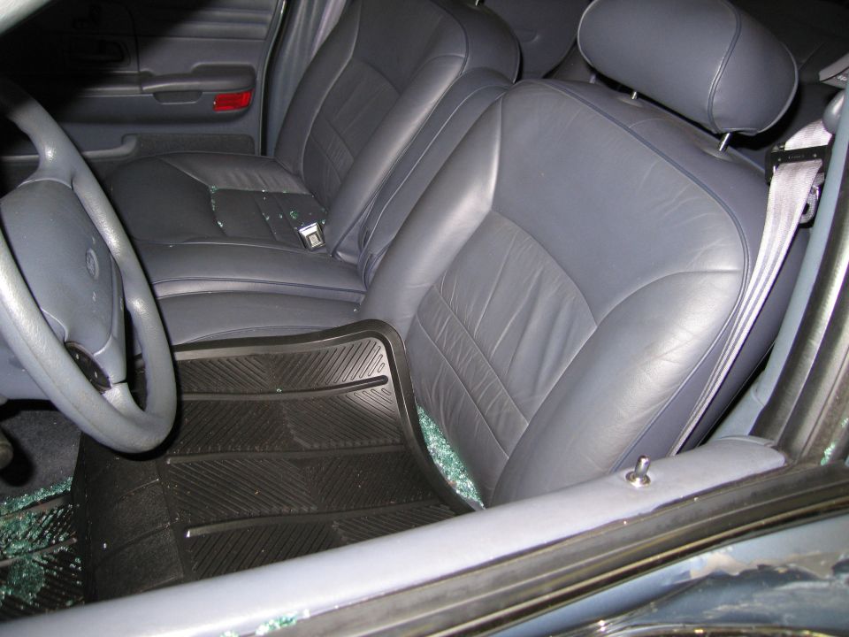 Car interior with gray leather seats, steering wheel, and broken glass on the floor
