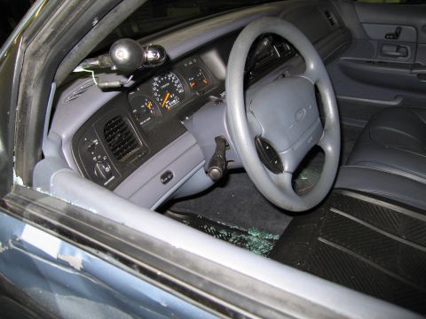 1991 Ford LTD Crown Victoria - Interior view of a damaged 1991 Ford Crown Victoria LTD, showing a broken window and debris on the floor.
