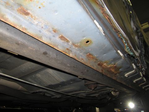 1991 Ford LTD Crown Victoria - Extensive rust and corrosion damage is visible on the rocker panel of this vehicle.