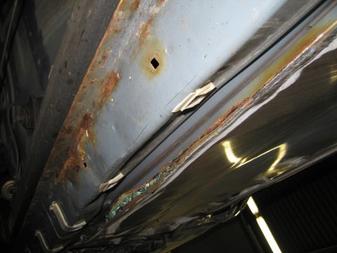 1991 Ford LTD Crown Victoria - Significant rust and corrosion are visible on the lower body panel of the vehicle.