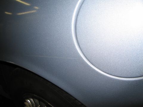 1991 Ford LTD Crown Victoria - Scratch on rear fender near fuel door of a silver vehicle.
