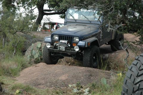 2001 Jeep Wrangler - Jeep Wrangler navigates rocky terrain, with another vehicle in the distance.