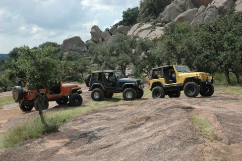 2001 Jeep Wrangler - Three Jeep Wranglers are parked on a rocky incline with trees and large boulders in the background.