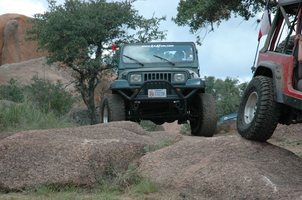 Green 2001 Jeep Wrangler front view, off-roading on rocks with another Jeep