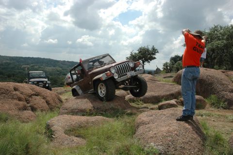 2001 Jeep Wrangler - Two Jeeps navigate a rocky off-road trail under a cloudy sky.