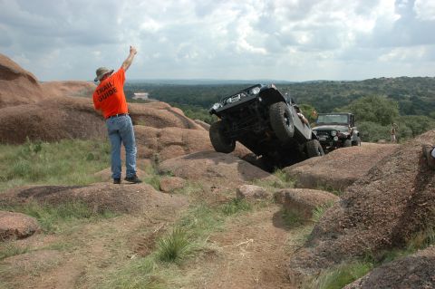 2001 Jeep Wrangler - Two Jeep Wranglers navigate a challenging rocky terrain, guided by a person in an orange shirt.