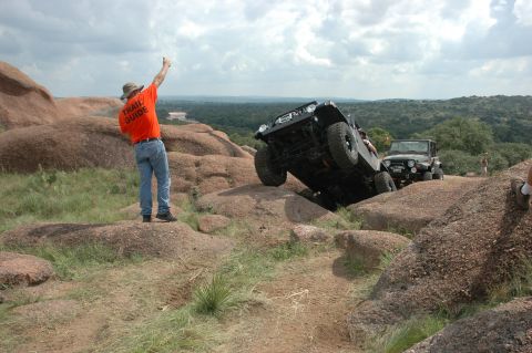 2001 Jeep Wrangler - A trail guide directs a 2001 Jeep Wrangler as it navigates a rocky incline, with another Jeep following behind.