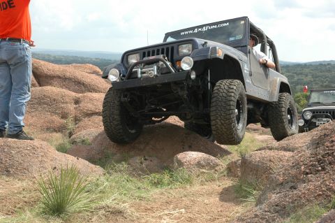 2001 Jeep Wrangler - A Jeep navigates a rocky off-road course with another vehicle following.