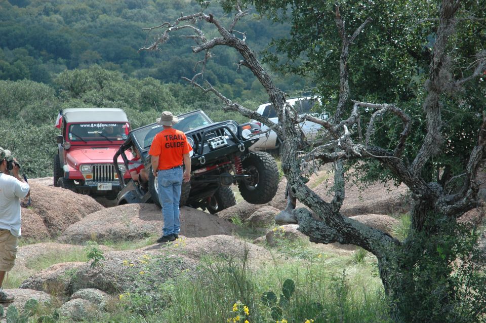 Black Jeep Wrangler with off-road modifications on rocky terrain, red Jeep Wrangler in background