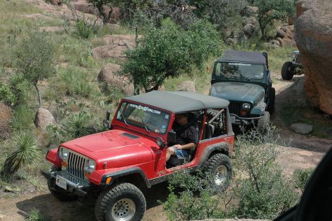 2001 Jeep Wrangler - Multiple Jeeps navigate a rough, off-road trail through a rocky, arid landscape.