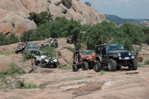 2001 Jeep Wrangler - A group of Jeep Wranglers navigate a challenging off-road course amidst a scenic, rocky environment.