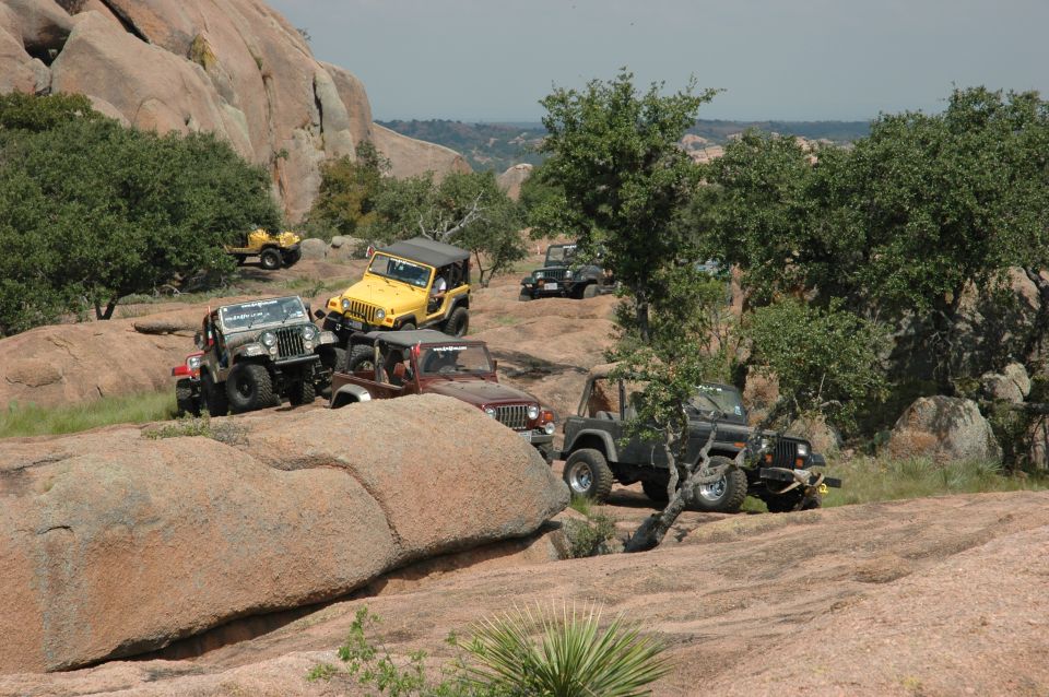 Several Jeeps parked on a rocky, wooded hillside