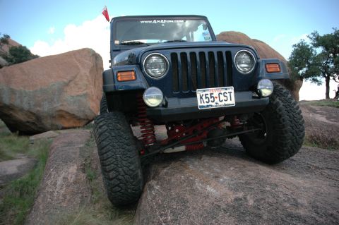 2001 Jeep Wrangler - A dark blue 2001 Jeep Wrangler navigates rocky terrain with its front end prominently displayed.
