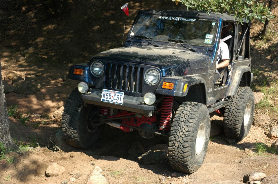 Dark blue 2001 Jeep Wrangler on rocky trail, front 3/4 view