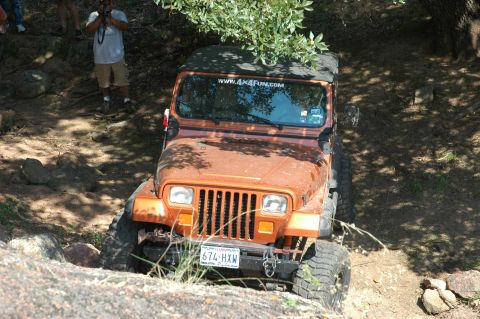 2001 Jeep Wrangler - A Jeep Wrangler navigates a challenging off-road course, with trees and rocks surrounding the path.