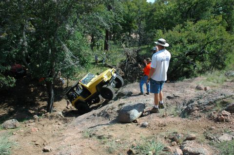 2001 Jeep Wrangler - A yellow 2001 Jeep Wrangler navigates a challenging off-road course, with spectators observing the action.