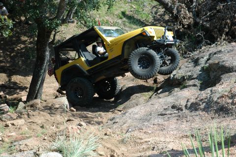 2001 Jeep Wrangler - A yellow Jeep Wrangler navigates a challenging rocky terrain, demonstrating its off-road capabilities.