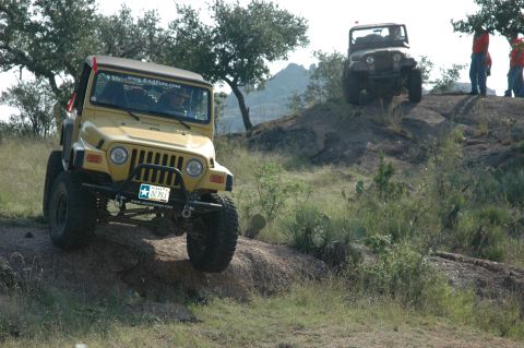2001 Jeep Wrangler - Two Jeep Wranglers navigate a challenging off-road course with rocky hills and sparse vegetation.