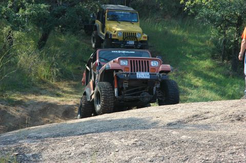 2001 Jeep Wrangler - Two Jeep Wranglers navigate an off-road trail, with the front vehicle climbing a steep, rocky incline.