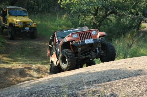 2001 Jeep Wrangler - Two Jeeps tackle a challenging off-road trail on a sunny day.