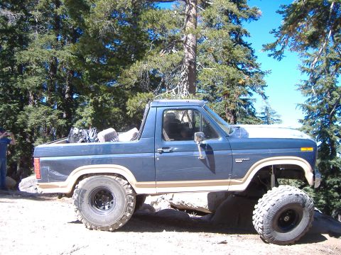 1986 Ford Bronco - This lifted 1986 Ford Bronco navigates rocky terrain with its large off-road tires and blue paint scheme.