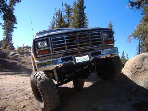 1986 Ford Bronco - Ford Bronco navigating a rocky off-road path under a clear blue sky.