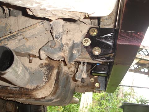1989 Ford Bronco - Close-up view of the vehicle's undercarriage, focusing on the exhaust system and a newly installed bumper bracket.