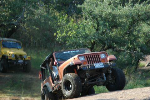 2001 Jeep Wrangler - Two Jeep Wranglers navigate a rocky, off-road trail with trees in the background.