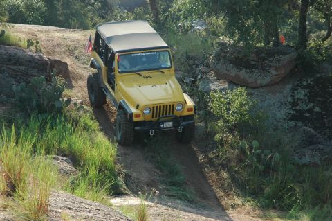 2001 Jeep Wrangler - Yellow 2001 Jeep Wrangler navigates an off-road trail with rocky terrain.