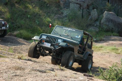2001 Jeep Wrangler - Two Jeeps off-roading on a rocky, grassy landscape.